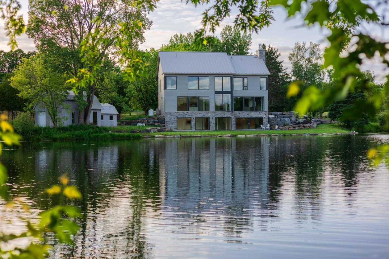 Résidence riveraine à Compton, mur de fenêtres sur le lac au coucher du soleil